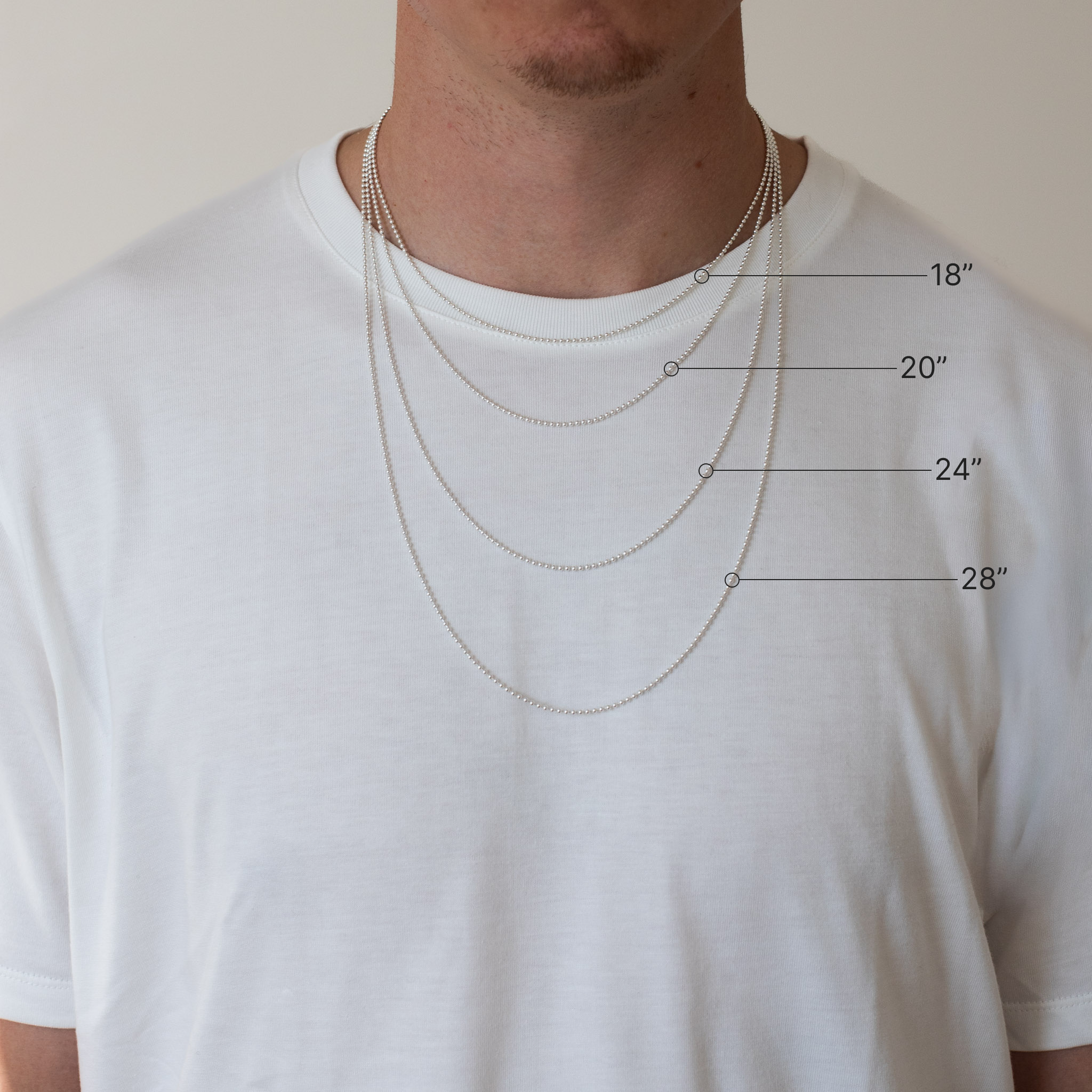 Man wearing four different length necklaces with measurements indicated on a plain background