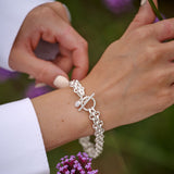 Close-up of a person wearing a silver bracelet with a floral background