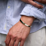 Close-up of a person wearing a black bracelet on a blue and white striped shirt.