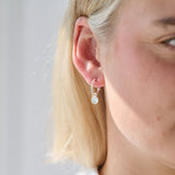 Close-up of a person wearing a silver birthstone hoop earring with a small round gemstone.