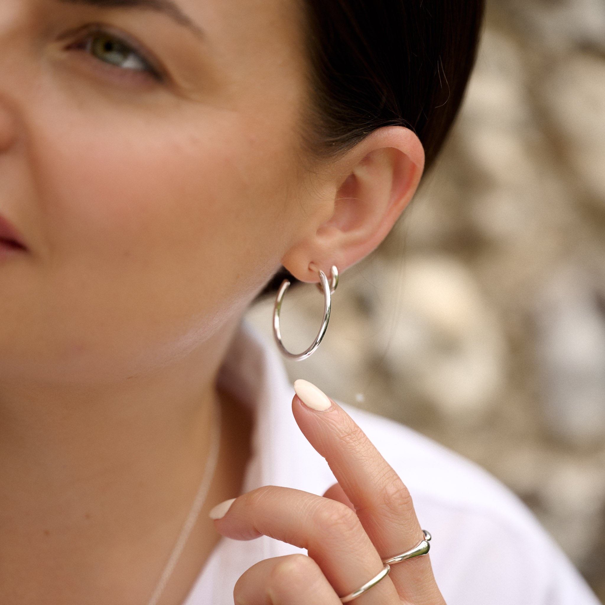 Close-up of a woman wearing silver hoop earrings with a blurred background