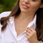 Woman wearing a necklace with a cross pendant outdoors