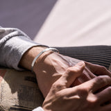 Close-up of two hands holding each other with silver bracelet on one wrist