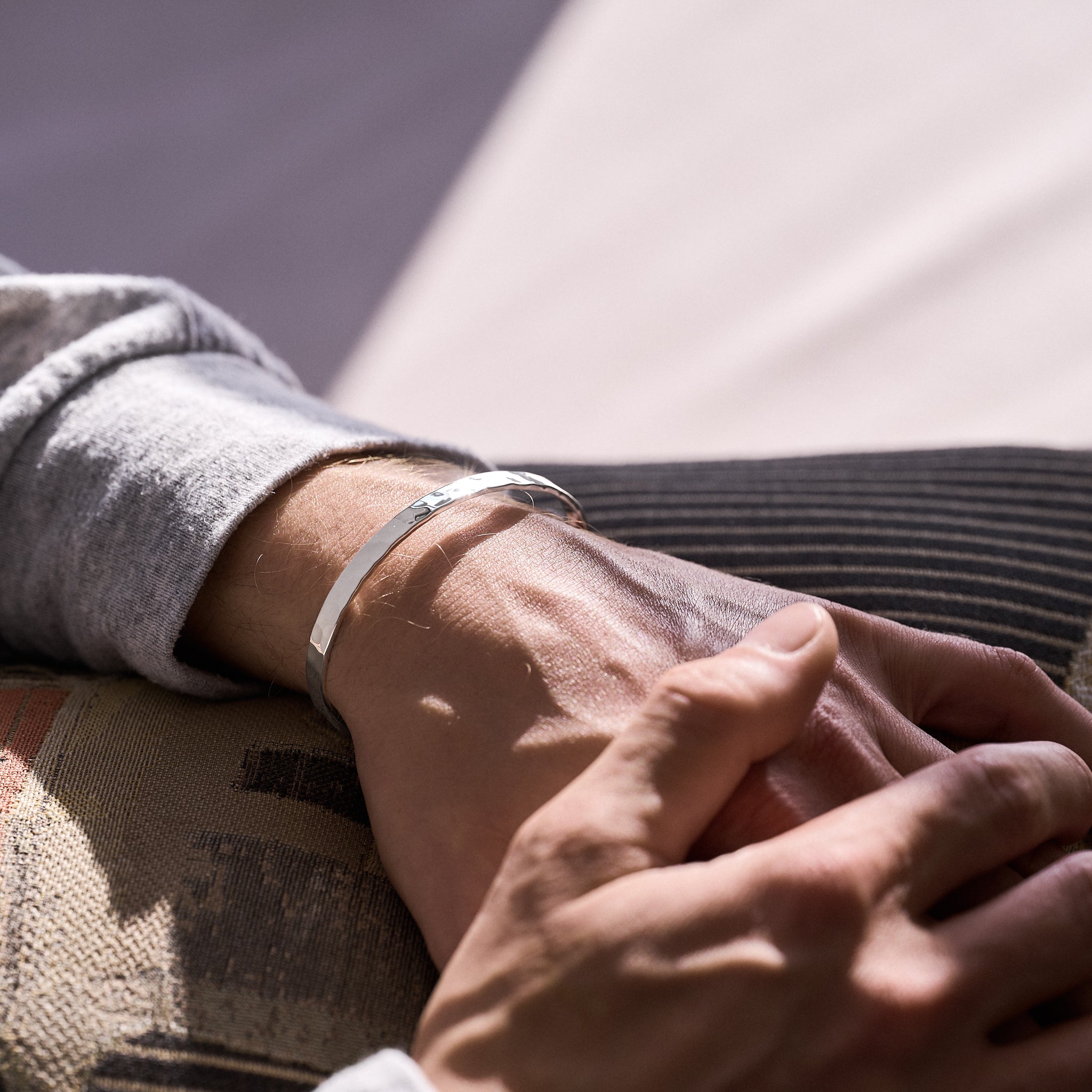 Close-up of two hands holding each other with silver bracelet on one wrist