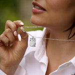 Person wearing a silver hammered dog tag necklace.
