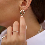 Close-up of a lady wearing silver hoop earrings and rings.
