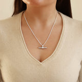 Silver necklace with a pendant worn by a person in a beige sweater.
