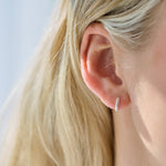 Close-up of an ear wearing a silver hoop earring with blonde hair.