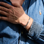 Person wearing a silver bracelet on a blue denim shirt background