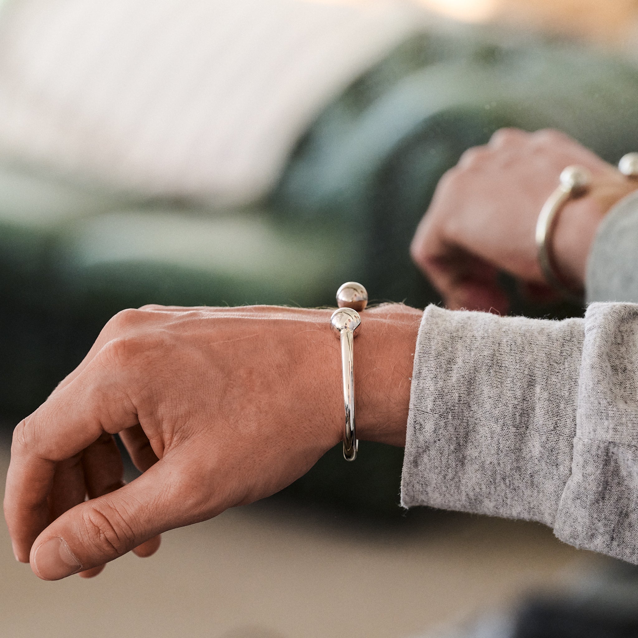 Close-up of a person's wrist wearing a silver torque bracelet in mirror