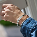 Person wearing silver bracelet on wrist wearing denim shirt
