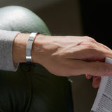 Person wearing a silver bracelet holding a book