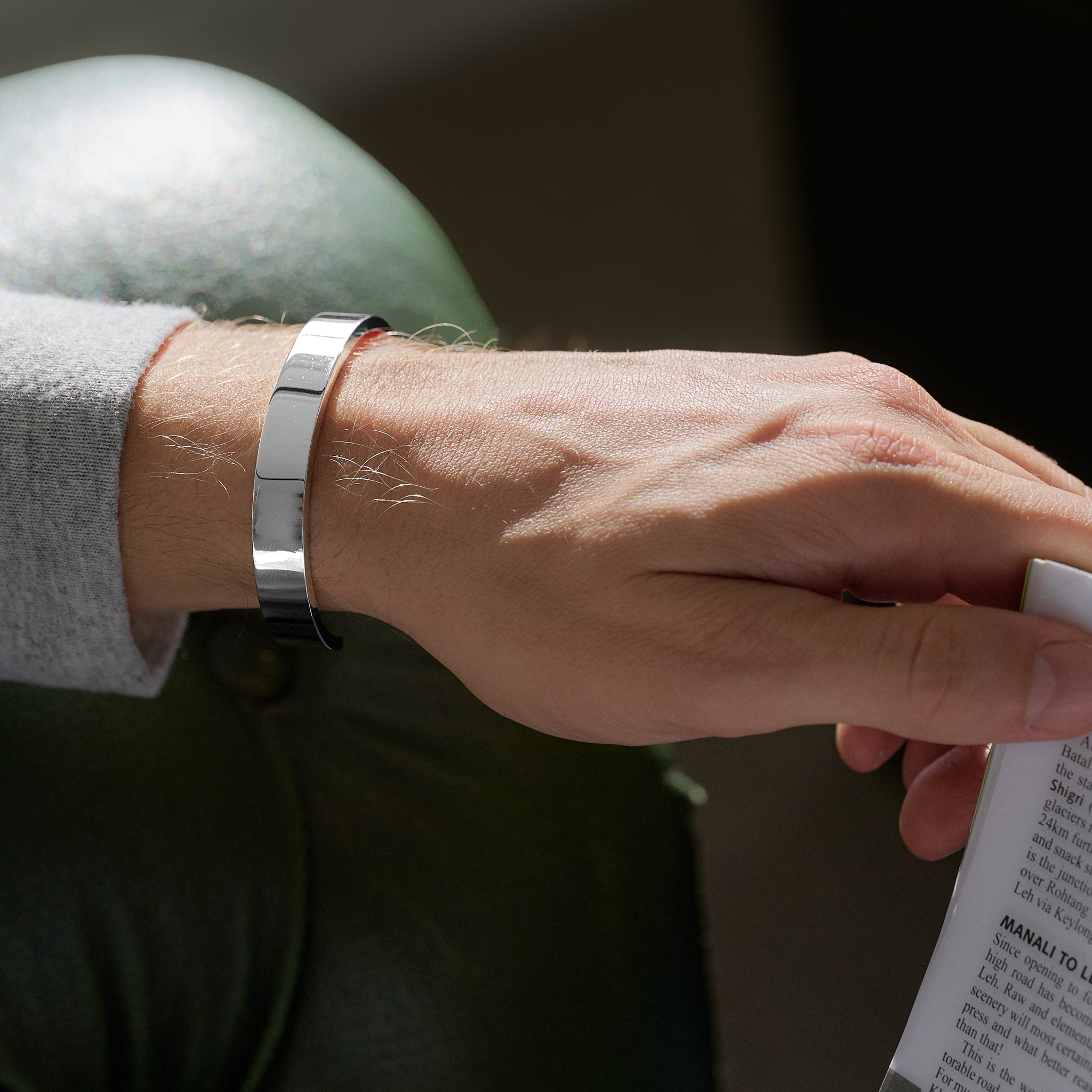 Person wearing a silver bracelet holding a book