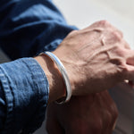 Close-up of a wrist wearing a silver bracelet with a blurred background
