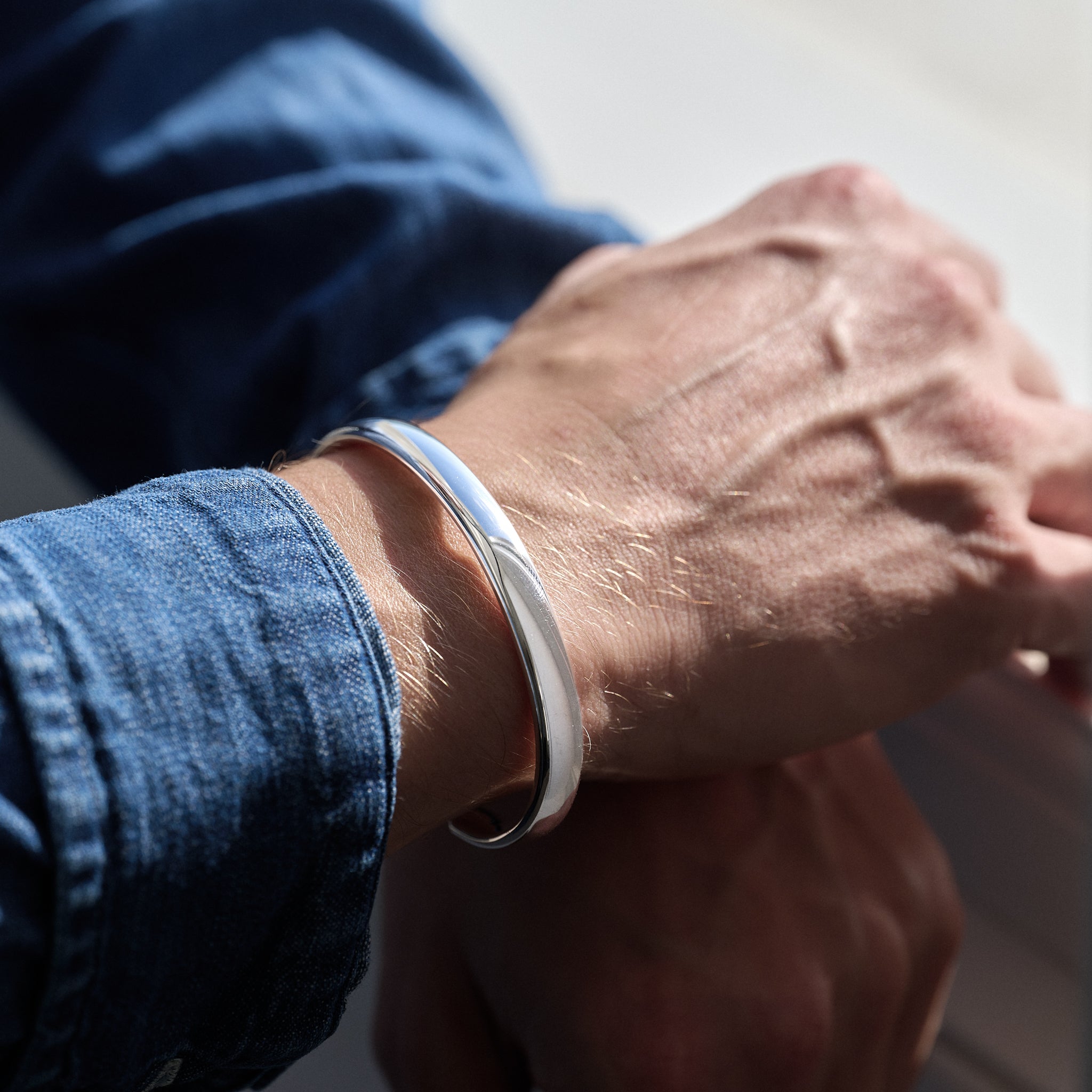 Close-up of a wrist wearing a silver bracelet with a blurred background
