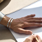 Hand on a light surface with silver chain bracelet and silver cuff bracelet on wrist