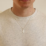 Necklace with a cross pendant worn by a person in a neutral setting