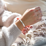 Hand wearing a hammered silver bracelet with a soft blurred background