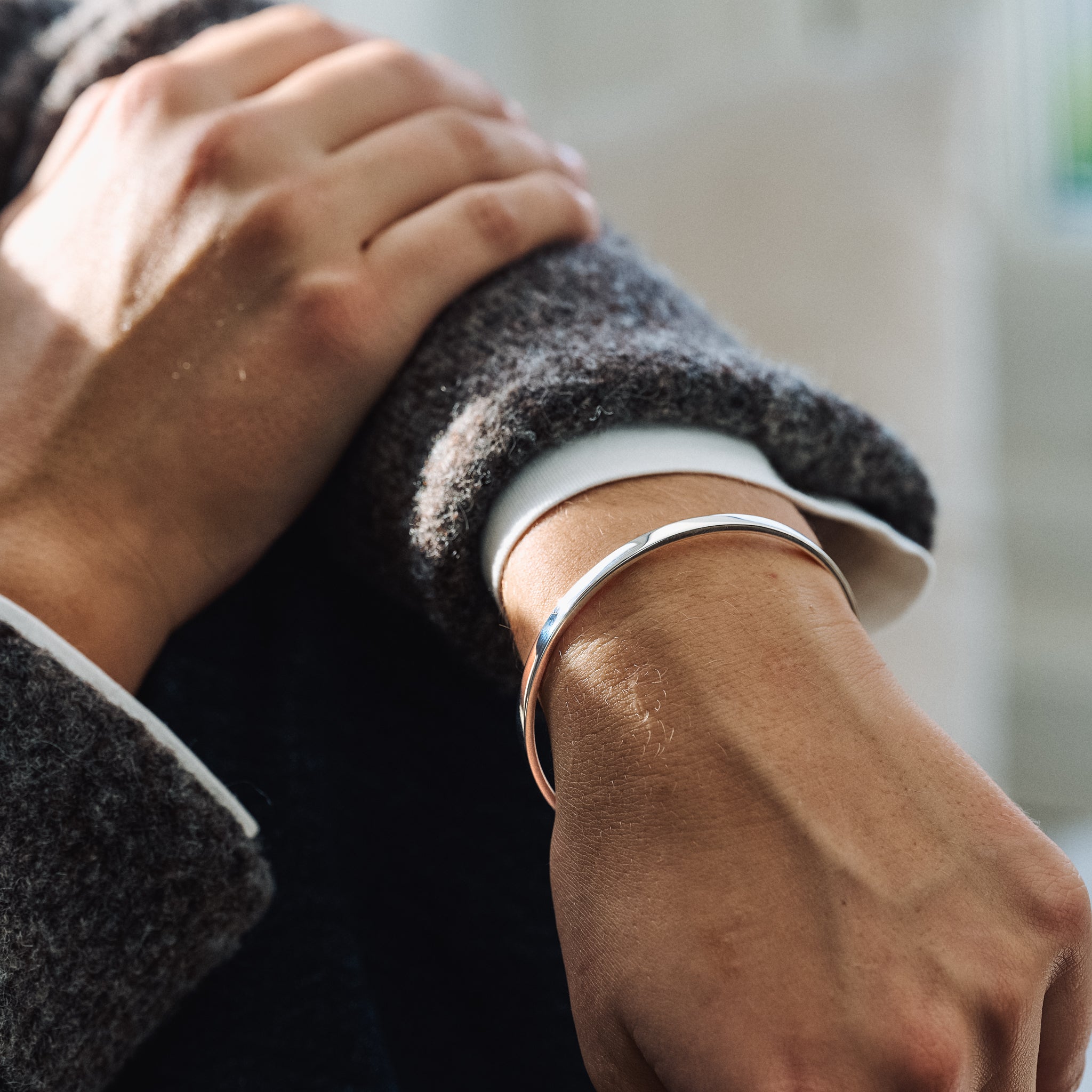 Close-up of a person wearing a silver bracelet on a blurred background