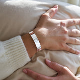 Person wearing a hammered silver bracelet on a light-coloured fabric background