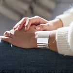 Close-up of a hammered silver cuff bracelet on one arm and a blurred background