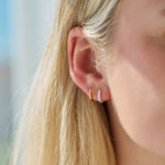 Close-up of a person wearing a gold hoop earring and silver hoop earring with a blurred background