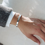 Silver bracelet on a person's wrist with a neutral background
