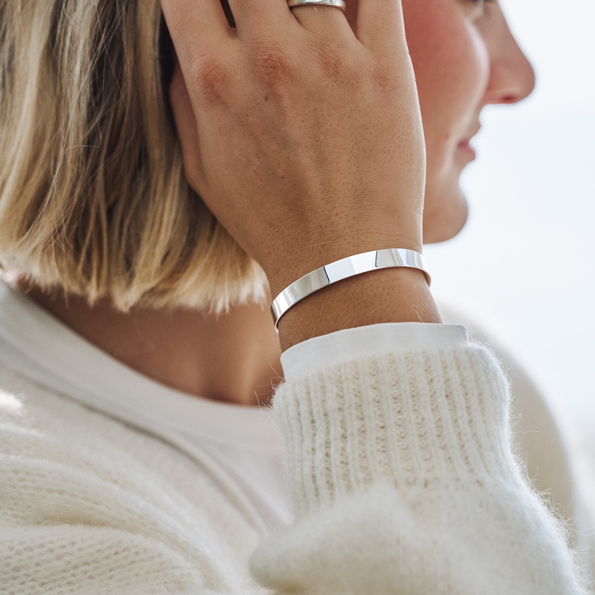 Close-up of a person wearing a silver bracelet and ring on a blurred background
