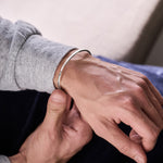 Close-up of a person wearing a silver bracelet on their wrist.