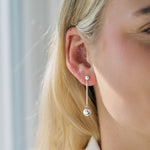 Silver drop earrings worn by a person with blonde hair, against a neutral background