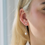 Silver drop earrings worn by a person with blonde hair, against a neutral background