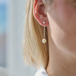 Women wearing pearl drop earrings with a blurred background