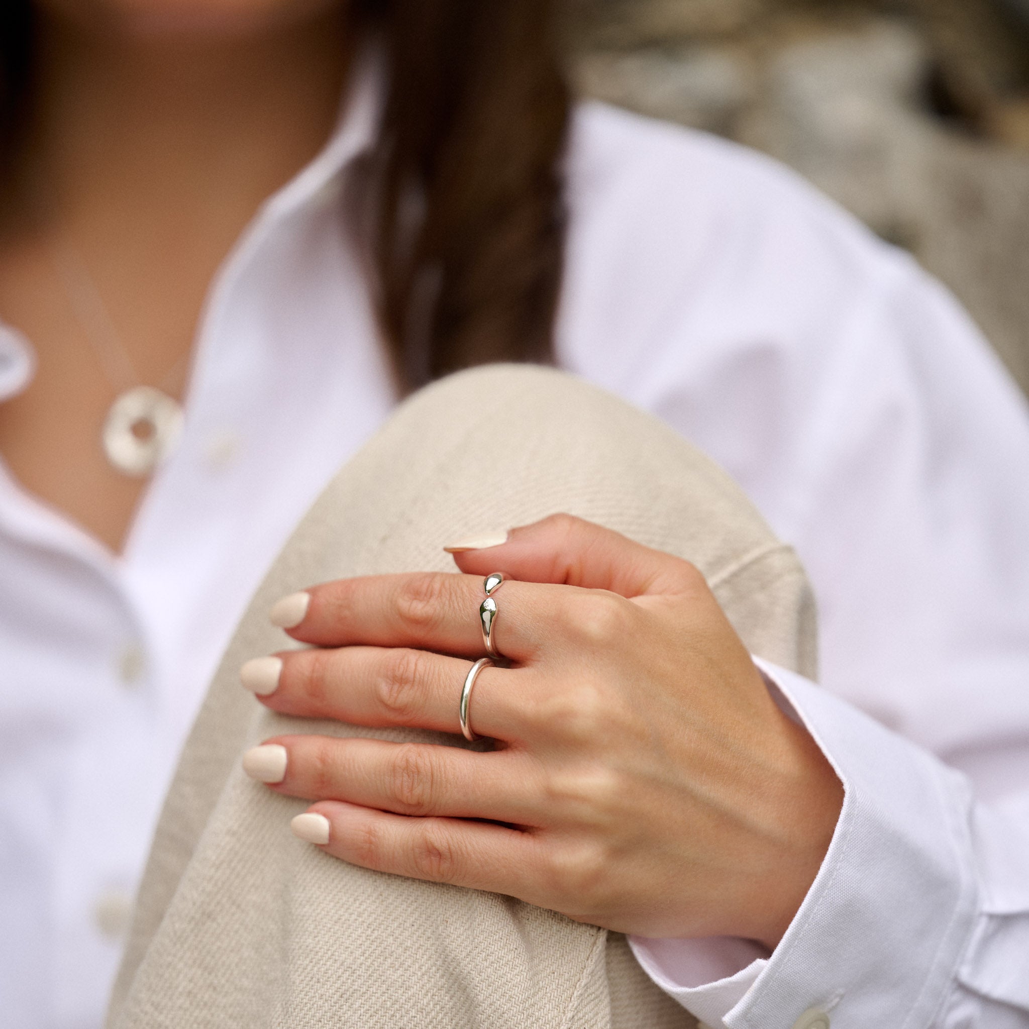 Close-up of a person wearing two rings on their fingers, with a blurred background.