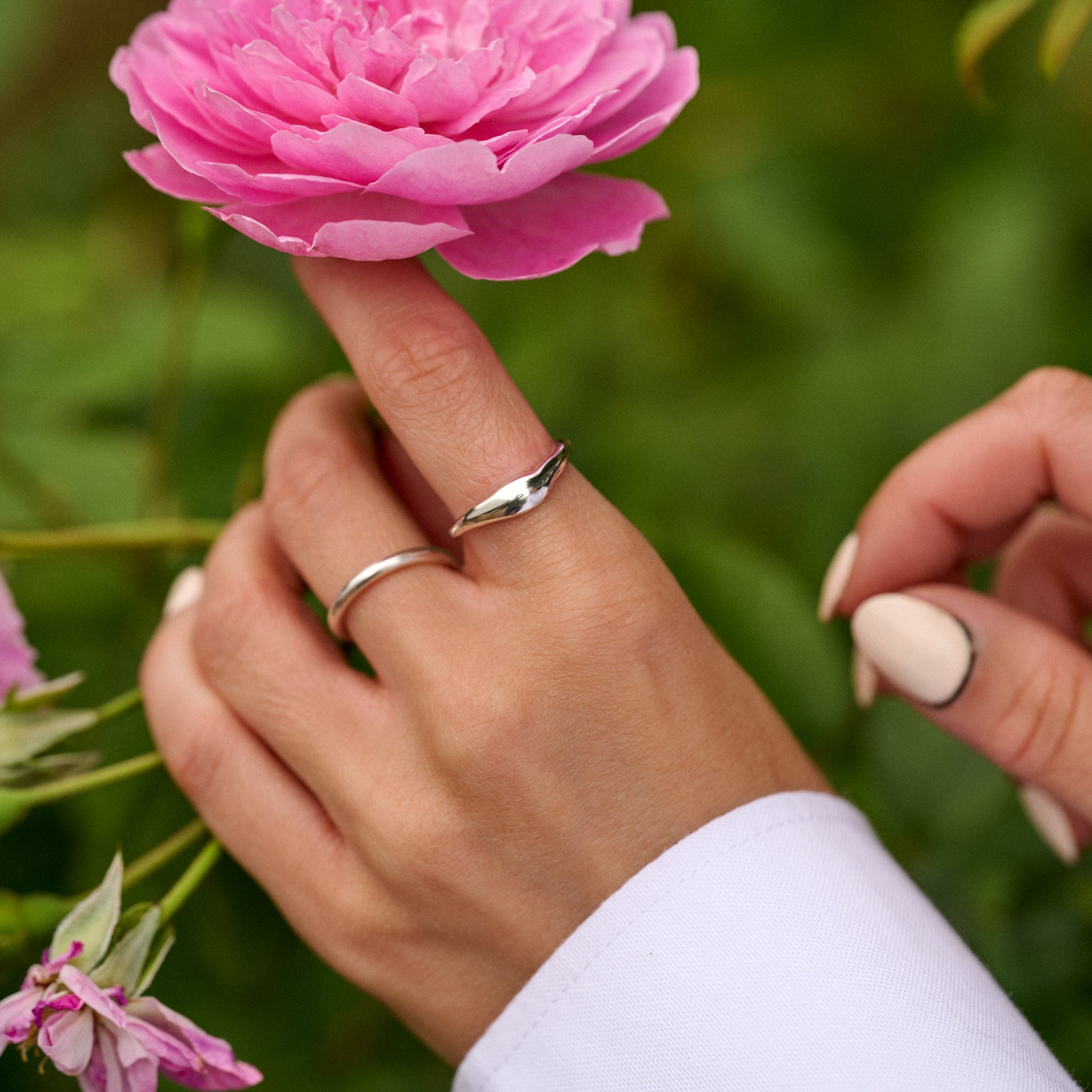 Close-up of a hand holding a pink flower with a blurred green background
