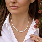 Woman wearing a silver necklace with a blurred background