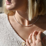 Close-up of a person wearing a silver chain necklace with a blurred background