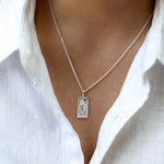 This image features a close-up view of a stylish Silver St Christopher Medallion Necklace. The necklace is crafted from high-quality silver, showcasing a rectangular medallion that beautifully engraved with the figure of St Christopher.