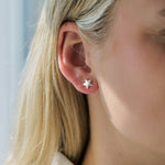 Close-up of a person wearing a star-shaped stud earrings with a neutral background