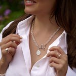 Woman wearing a silver necklace with a blurred outdoor background