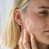 Close-up of a woman wearing a gold hoop earring with a blurred background
