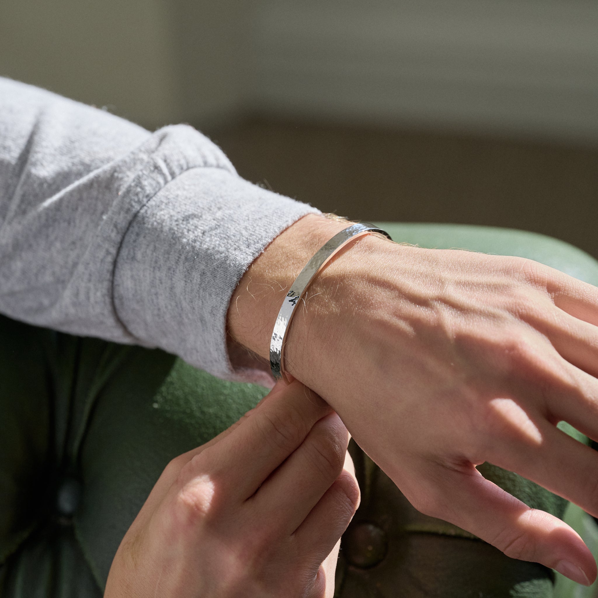 Person wearing a silver bracelet on a blurred background