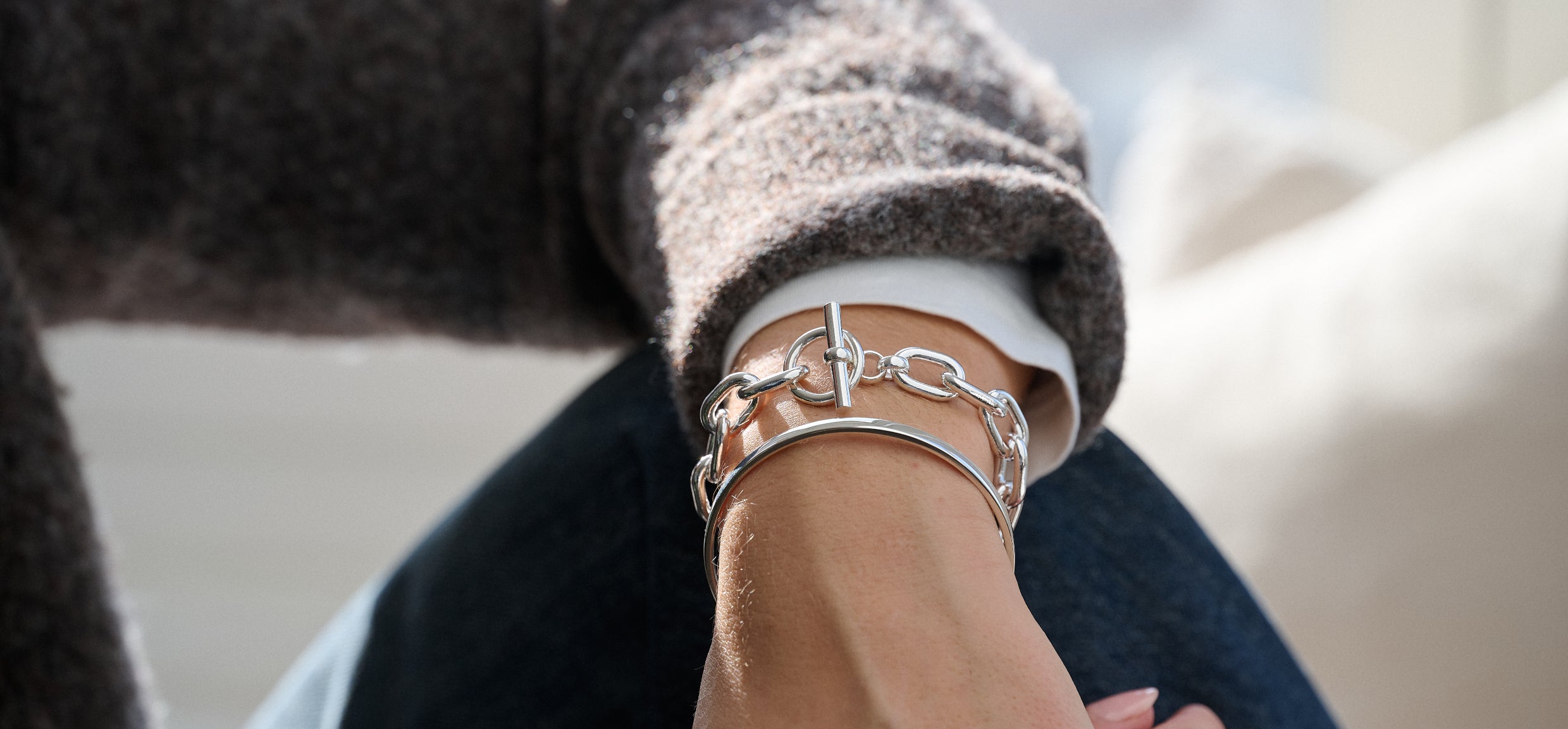 Person wearing a silver bracelet on a blurred background