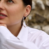 Lady wearing gold hoop earrings with a natural background