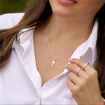 Woman wearing a necklace with a cross pendant outdoors