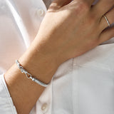 Silver snake bracelet on a wrist with a white shirt background