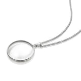 A silver  necklace with a round magnifying pendant on a curb chain, shown on a clean white background. 